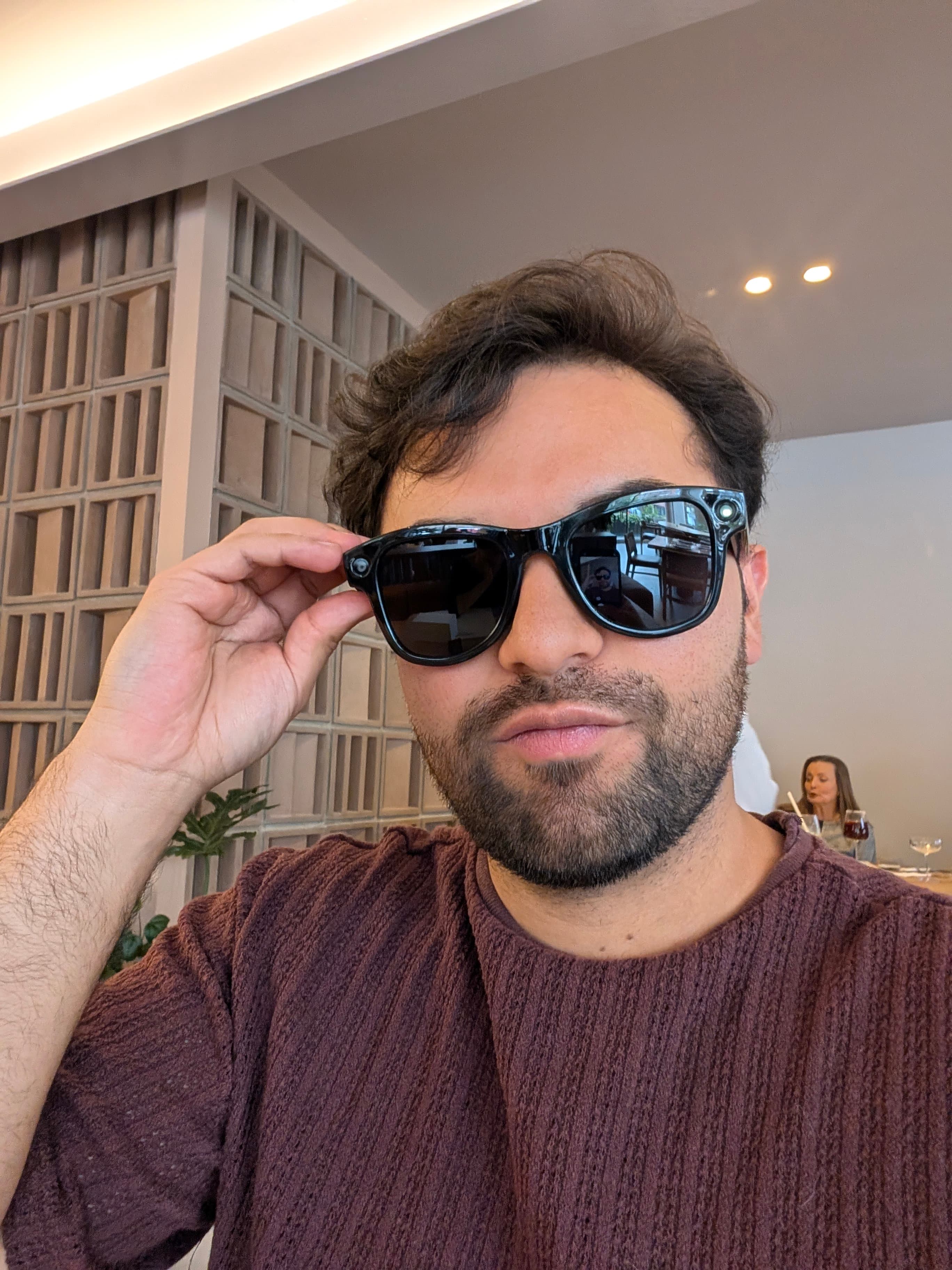 Hombre ajustándose las gafas de sol AXIS en un restaurante