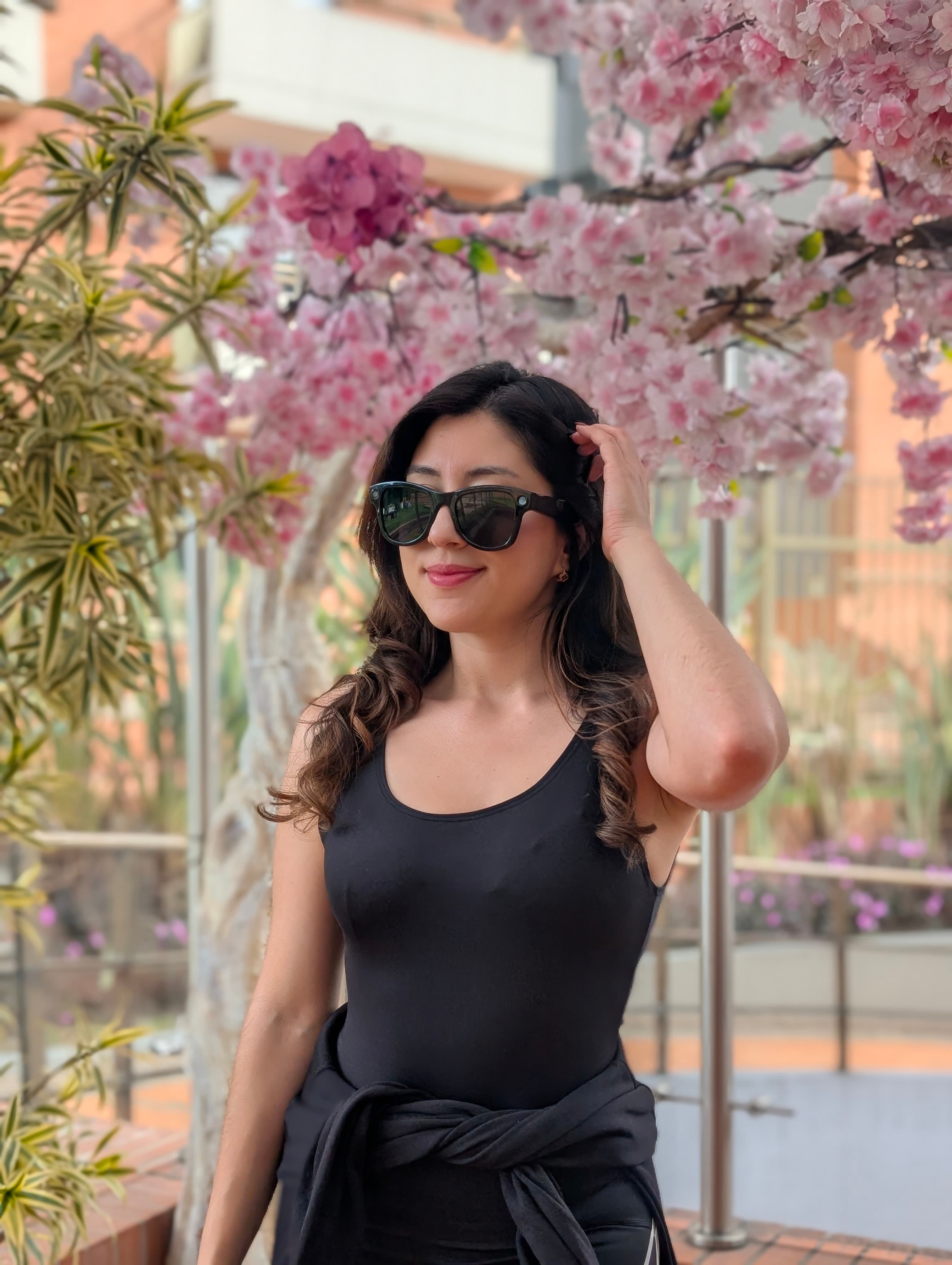 Mujer con gafas de sol AXIS frente a un árbol en flor